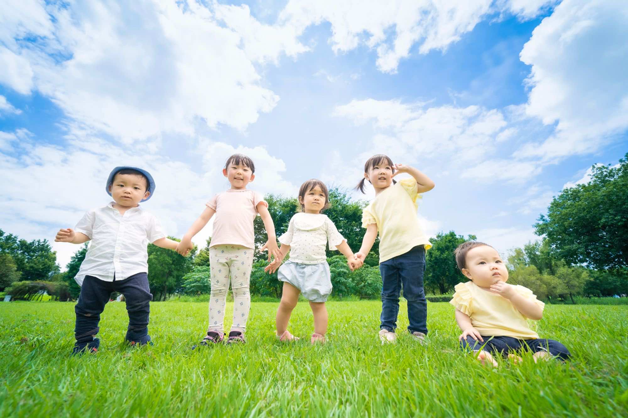 手を繋いでポーズをする5人の子どもたち