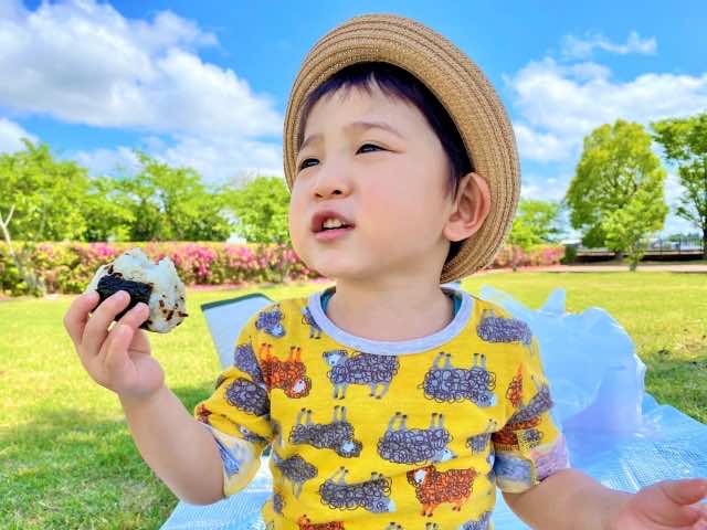 自然の中でおにぎりを食べている男の子