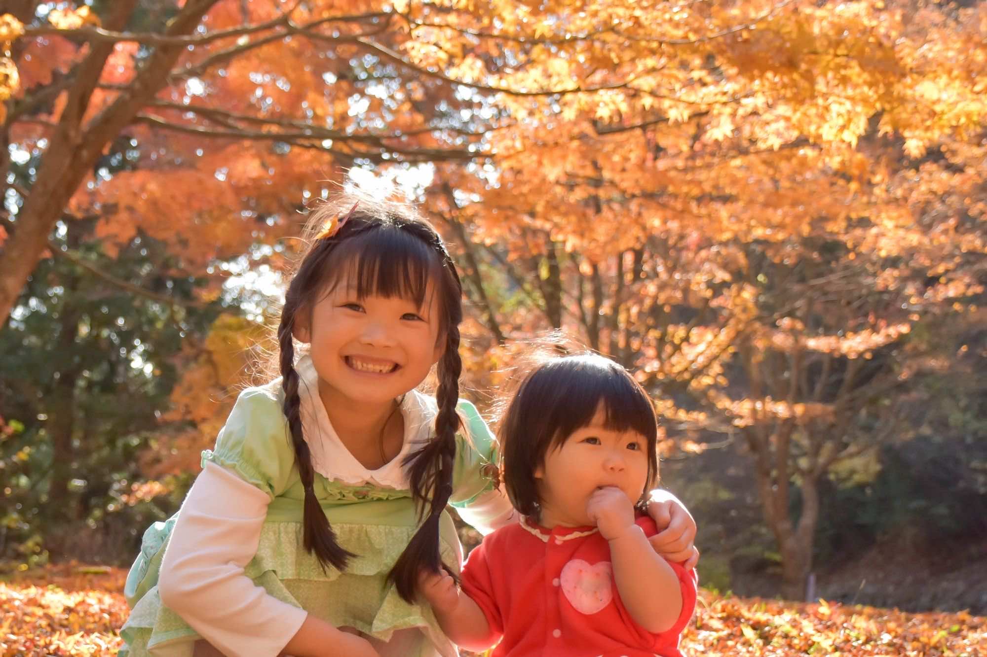 紅葉の下で笑顔を見せる姉妹
