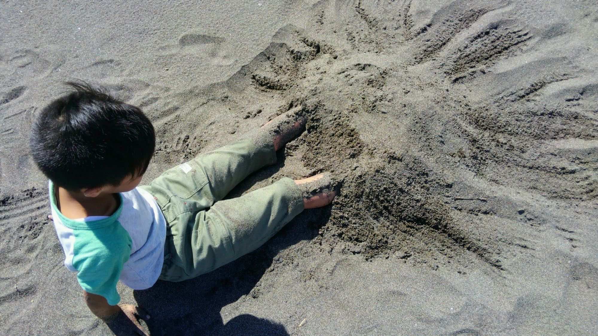 砂浜で砂に足を入れて遊んでいる様子
