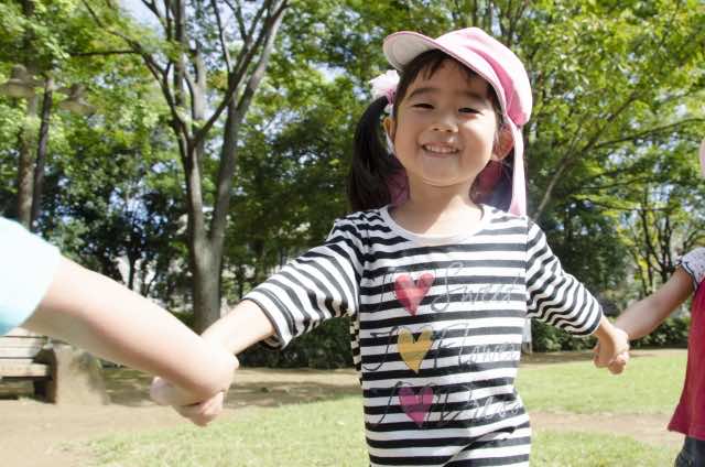 手を繋いで歩くピンク色の帽子を被った女の子